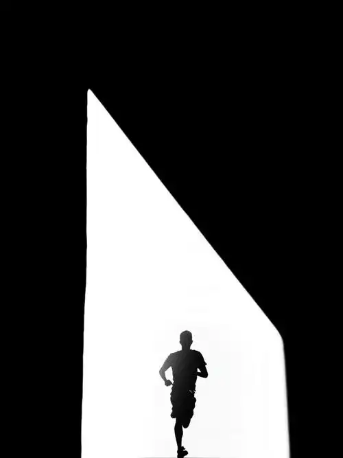 阳光下的影子,建筑的巨大框架里,跑步的身影映在墙上,形成了明暗对比.