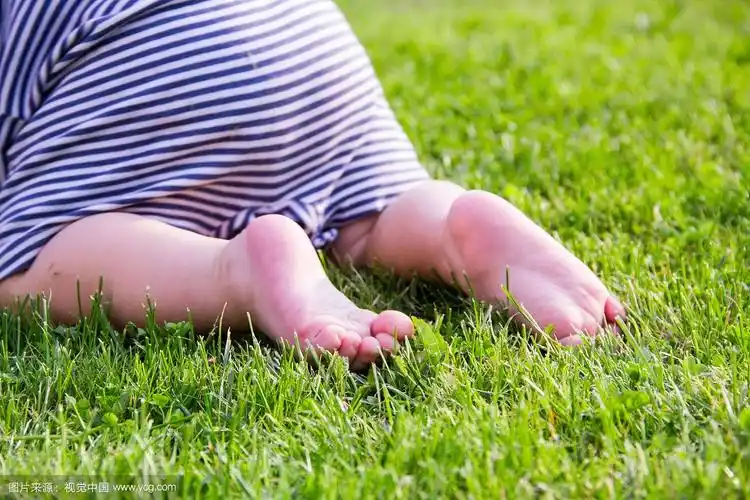 关闭了.快乐的孩子脚赤脚在绿色的草地上.