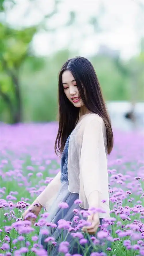 人像摄影紫花旁少女秀发飘飘笑容可掬