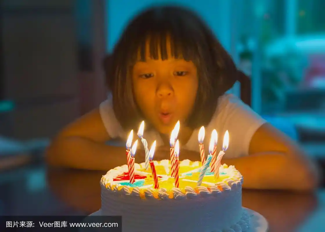 可爱的亚洲女孩许愿和吹蜡烛在生日蛋糕在家里与家人聚会.