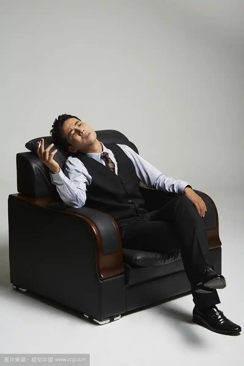 西装男坐在沙发上抽烟的照片