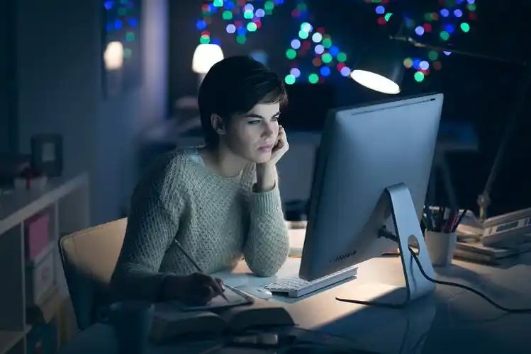 一个女人深夜在电脑前加班深夜工作和学习的年轻女子, 她正在与她的