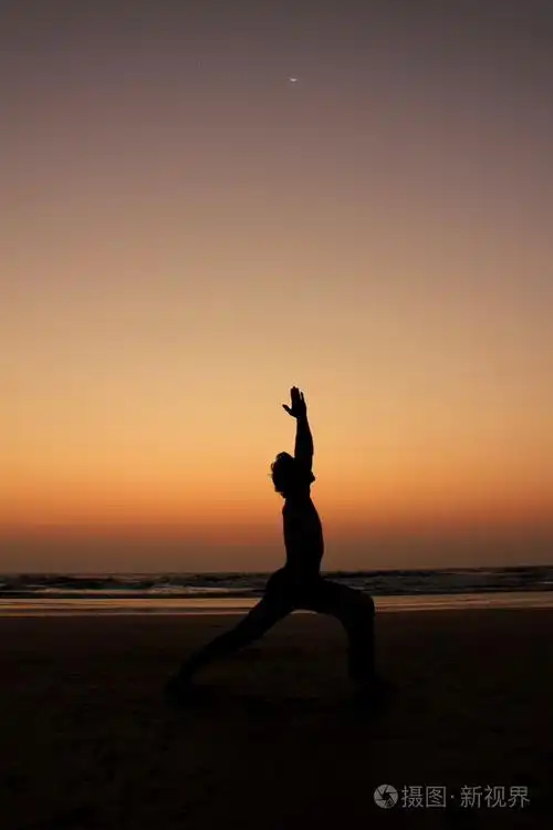 在日落的海边背景上的瑜伽姿势的男人剪影.月光下的战士