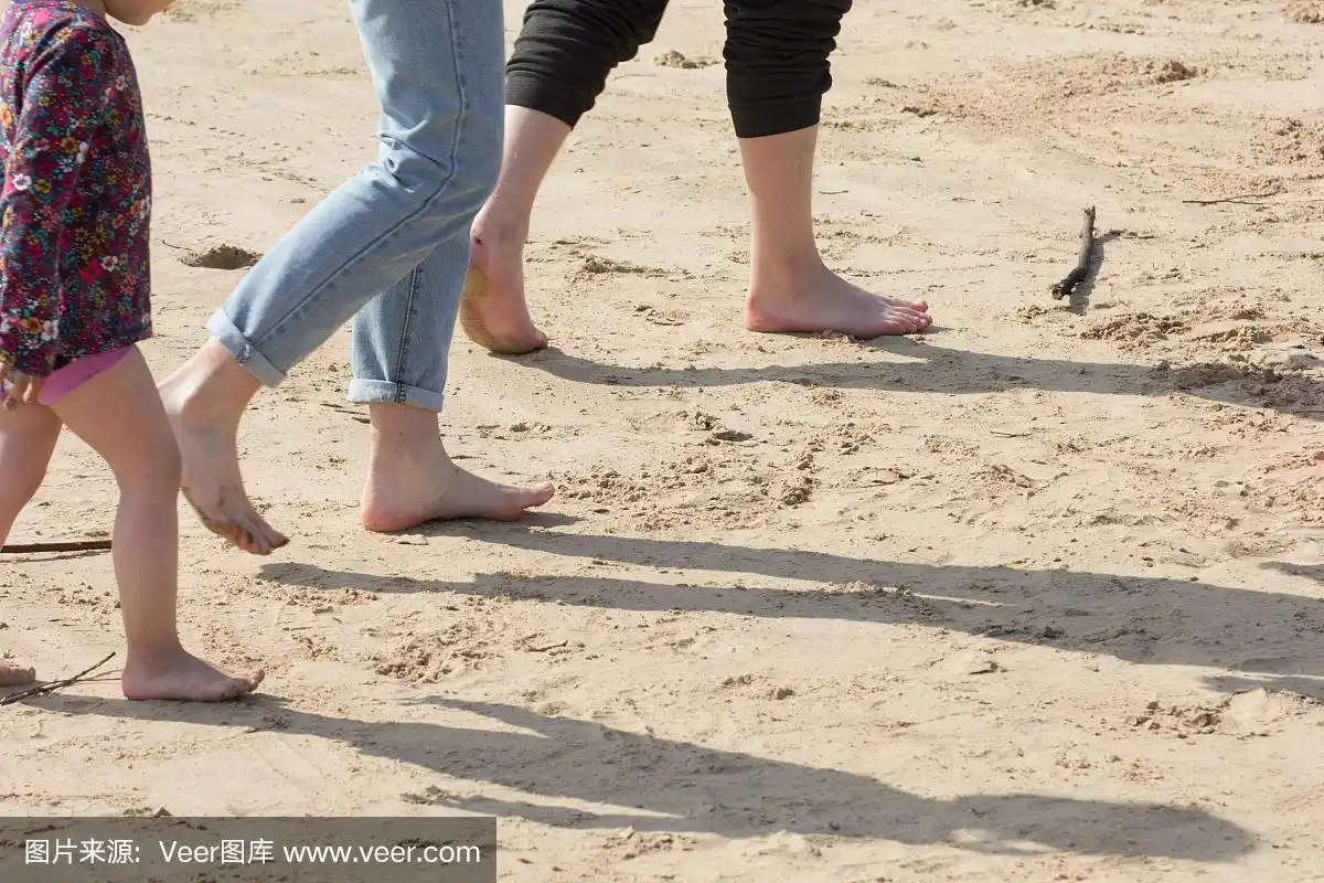 孩子的脚,女人的脚和男人的脚赤脚走在沙滩上