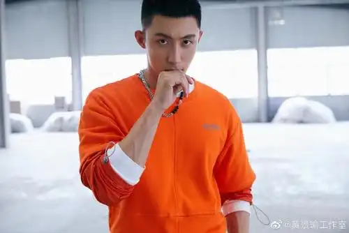 照片中,黄景瑜留着一个考验颜值的寸头,上身穿橙色上衣,下身穿着黑色