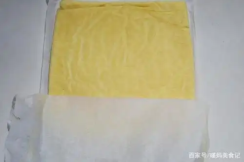 9.在烤好的蛋糕上铺上一层油纸,把蛋糕倒过来,撕去蛋糕底部的油纸.