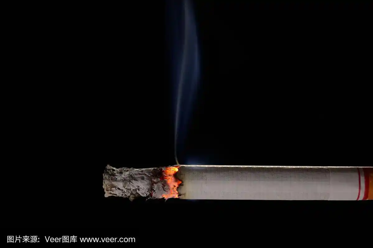 在黑色背景上点燃并燃烧着的香烟