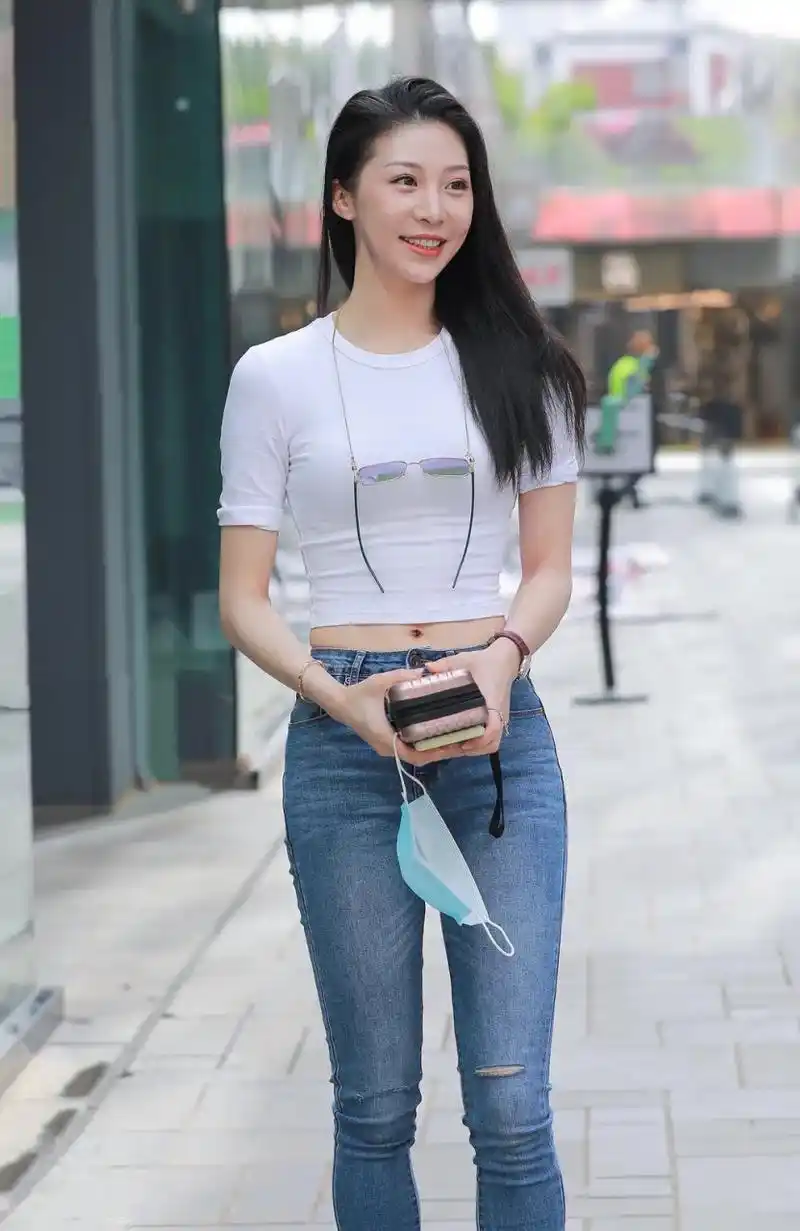 街拍到一位清新自然的美女,身穿白色短t恤,搭配高腰蓝色牛仔裤,脚穿