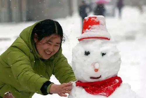 1月26日,一位女士在家门口堆雪人.新华社发(王家国 摄)