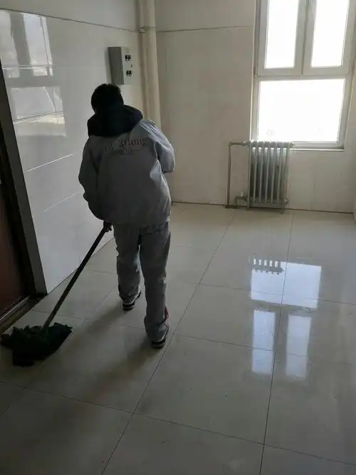 女生手里拿着抹布,全心全意地擦着通道的墙壁,男生手里拿着墩布,擦着