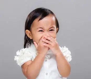 用手指对嘴的手势孩子张开嘴吃巧克力糖亚洲美女小女孩捂着嘴要呕吐