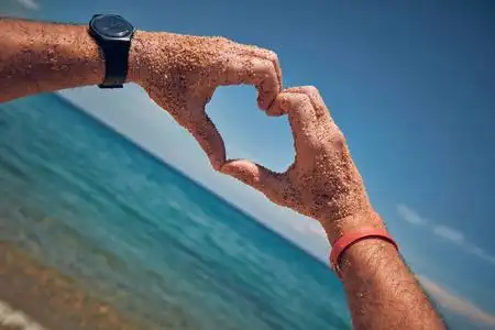地上半个心符号手在热带沙地上做心形符号的人照片