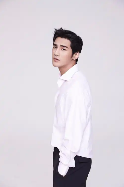 姜潮在镜头中身穿粉色的衬衣搭配简约时尚的黑色长裤帅气逼人.