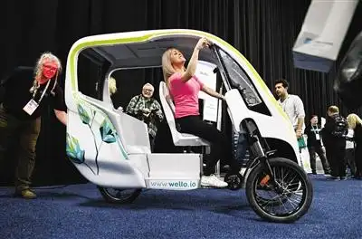 1月5日,在美国拉斯维加斯,人们体验一款太阳能电动助力三轮车.