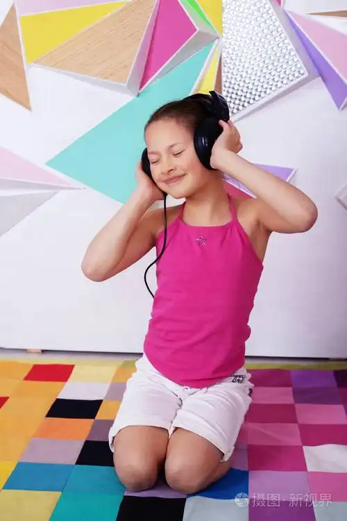 美丽快乐的儿童女孩通过耳机听音乐.童年与音乐的概念