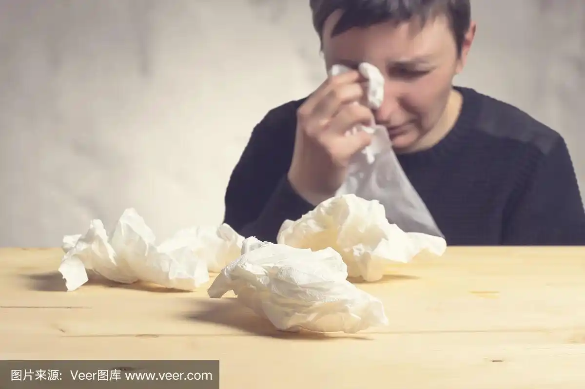 伤心的女人哭着擦眼泪,选择性的把纸巾放在桌子上.