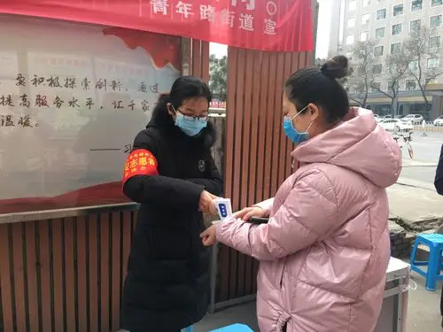 志愿者对进出居民进行体温测量