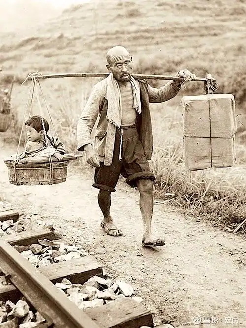 1944年的中国一男子挑着扁担一头是孩子一头是货物走在铁路边上