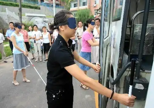 7月15日,参加培训的人员戴着眼罩体验盲人上公交车的感觉.