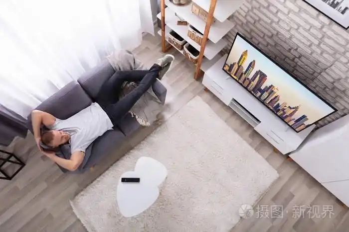 一个年轻人躺在沙发上看电视