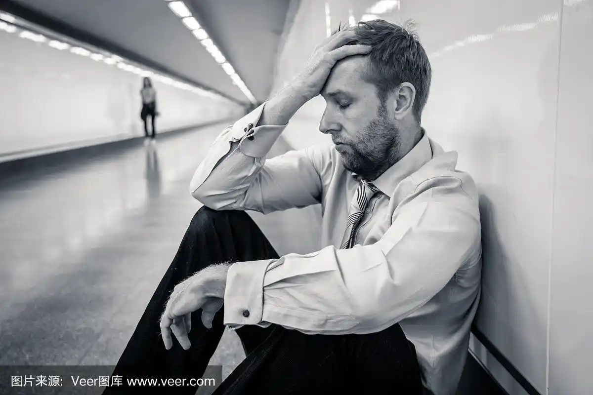 绝望悲伤的年轻商人承受着情感上的痛苦悲伤和深深的抑郁独自坐在隧道