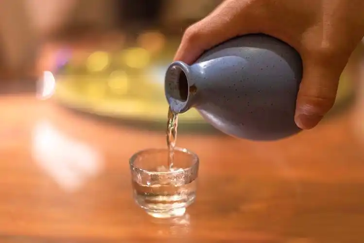 拿着酒瓶在饭桌上朝酒杯中倒酒图片下载