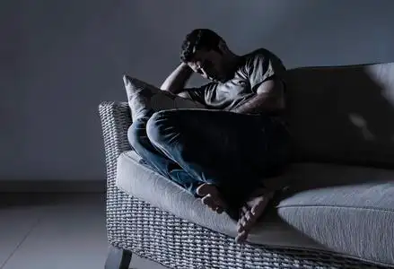 悲伤的厨师的男人在哭泣年轻的绝望的悲伤和沮丧的男人在家沙发上悲伤