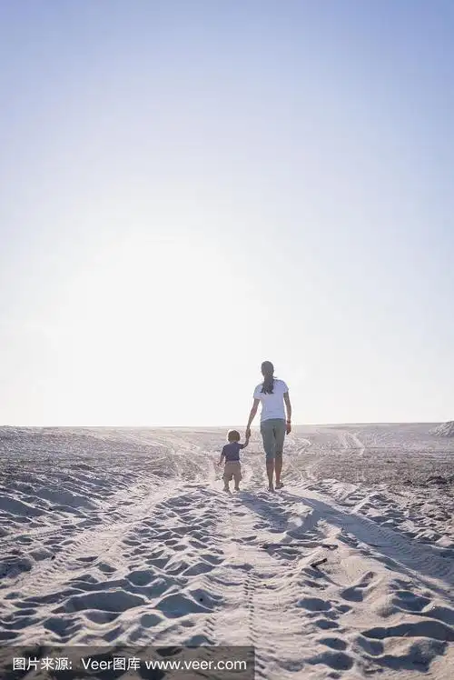 母亲和年幼的儿子牵着手在海滩上