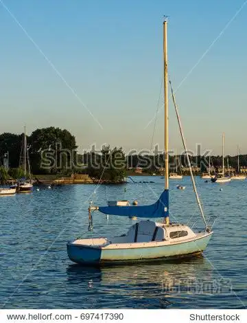 a single sail boat moored on lake champlain on a summer evening