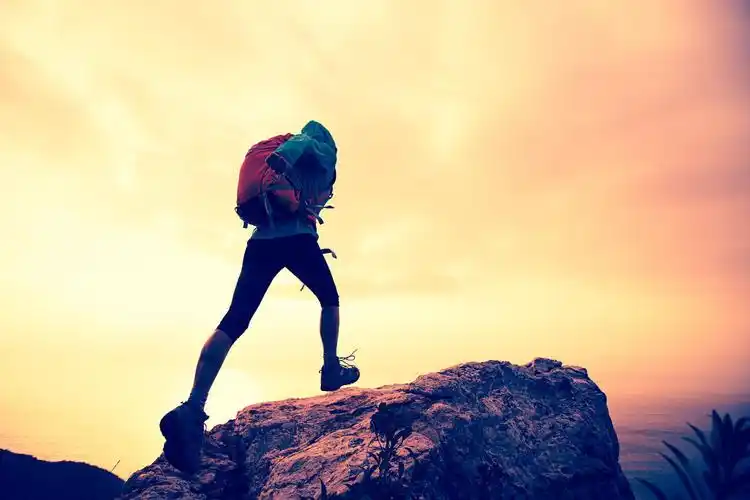 在海边的山峰上攀爬的徒步旅行者