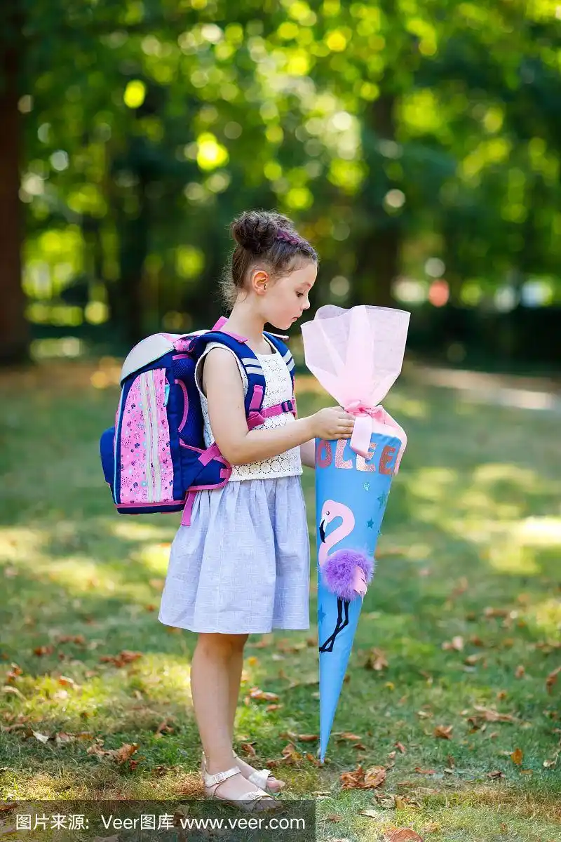 快乐的小女孩背包或挎包和大书包或圆锥在德国传统的第一天学校.