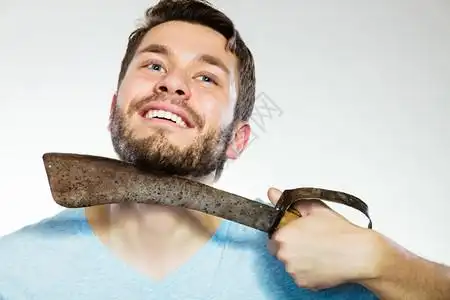 切橙子长胡子的帅哥刮家伙用大刀刮灰色背景的背景