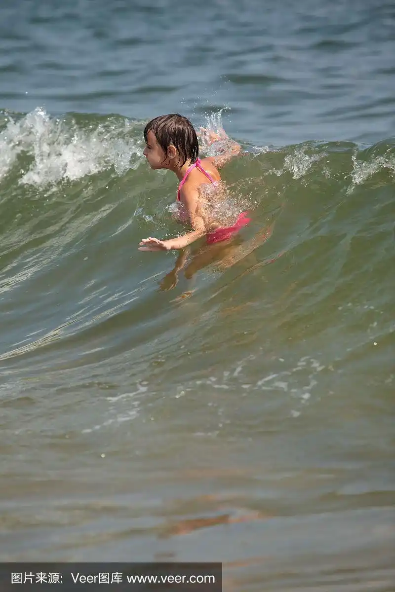 小女孩在海里的波浪下游泳