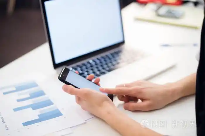 在办公室使用手机和笔记本电脑的女人手