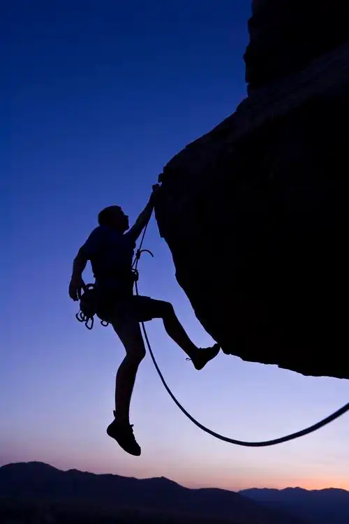 夕阳下的莫哈韦沙漠有一位正在攀登的登山者奋斗精神努力努力坚持不懈