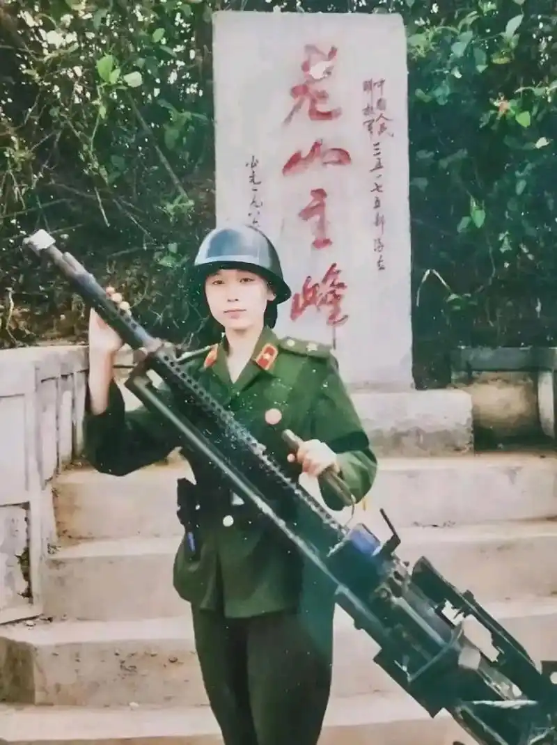 80年代,一位英姿飒爽的女兵在老山主峰碑前留影,照片中她穿着一身绿