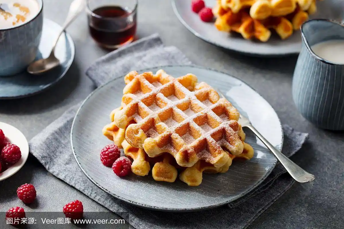早餐比利时华夫饼配枫糖浆和新鲜覆盆子.灰色背景.