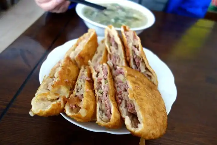 先推荐当地的美食郓城何家壮馍二两左右的牛肉馅被和好的面包裹起来擀