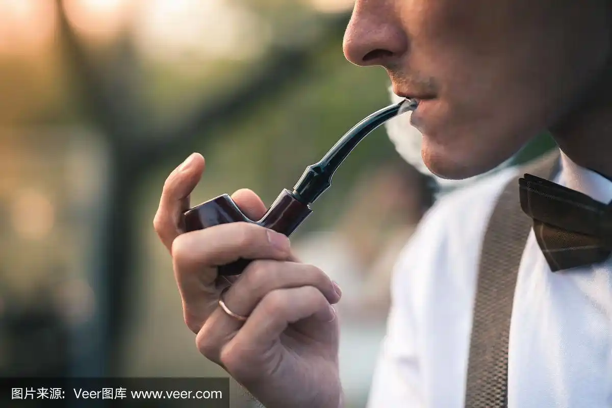 英俊的明日男子抽着烟斗