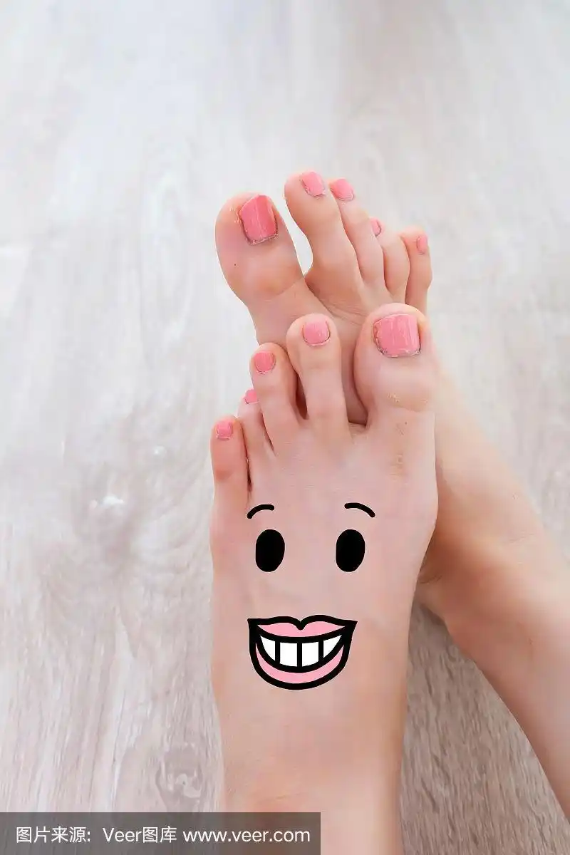 脚趾上画的笑脸.近距离女性赤脚在木地板背景伟大的任何用途.