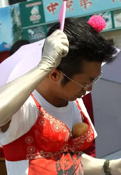 一个中年男子穿着塞了两个苹果的红色胸罩在公园内游走,十分雷人,被