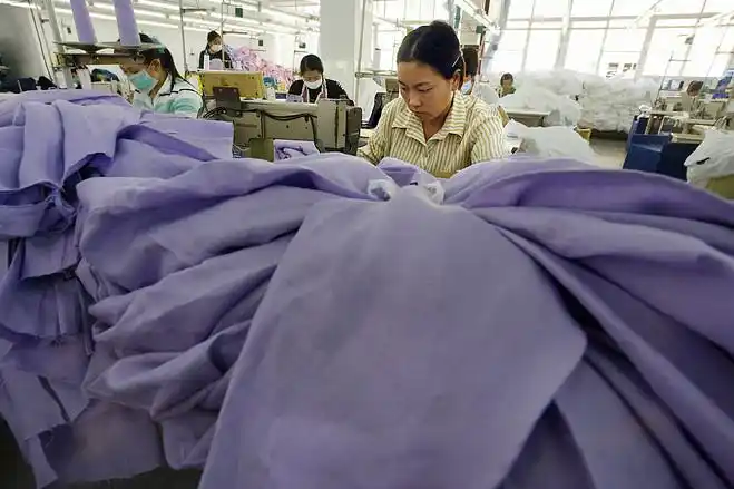 照片摄于2004年12月13日,一名女工在深圳城郊的一家纺织厂里工作.