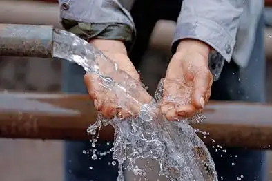11月20日,南岭村打井工程竣工仪式现场,一位村民正在用手接水.