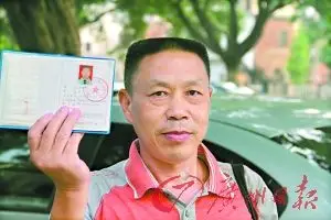 朱国秋拿着自己的保安上岗证,表示自己将继续争取合法权益.