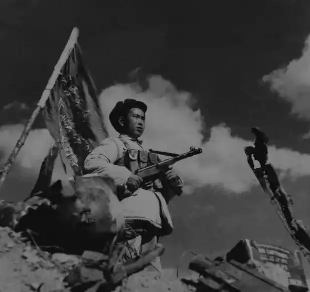 志愿军第15军官兵将布满381个弹孔的战旗插在上甘岭主峰阵地