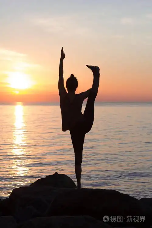 照片 在瑜伽体式上早上海滩, 漂亮合适的女人实践健身 exrxise 石头