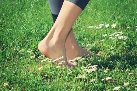 女人赤脚走在绿草上.照片