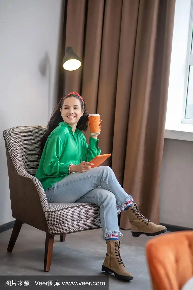 一个漂亮女人盘腿坐在椅子上.