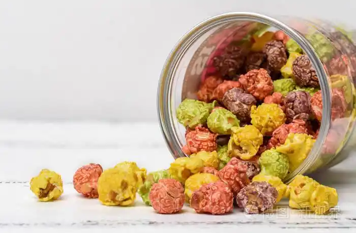 彩色焦糖爆米花散落在白色的木质背景上