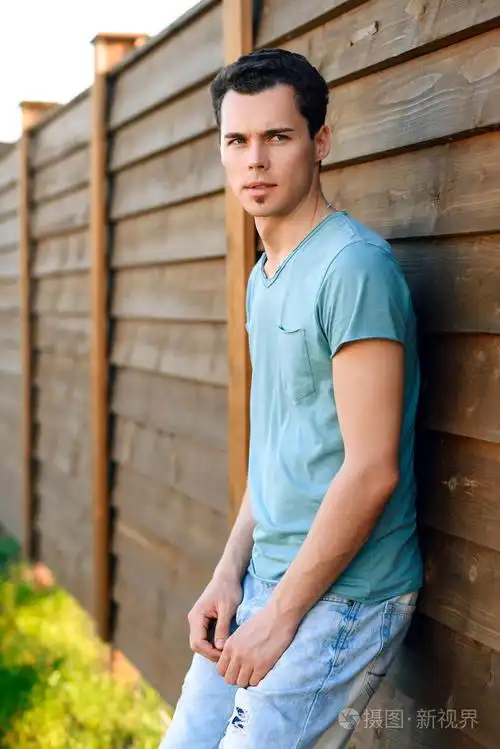 猛男年轻的帅小伙室外在日落时一件蓝色衬衫的肖像